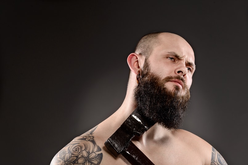 topless bearded man grooming his beard